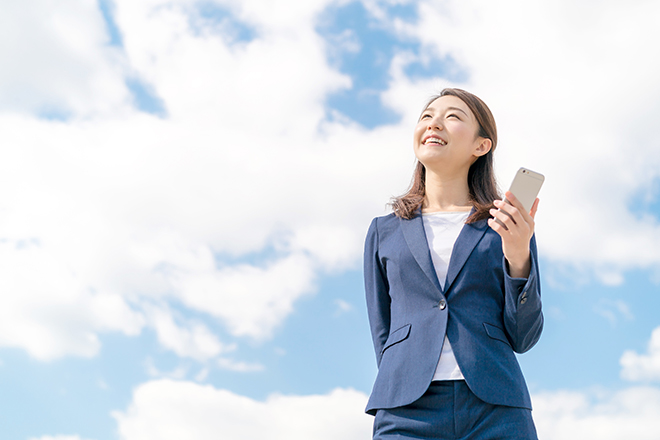 スマホを持って空を見上げる女性